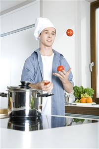 man juggling with tomatoes in kitchen