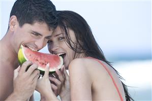 couple eating watermelon on beach