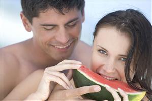 Pareja en la playa comiendo sandia. Primer plano.