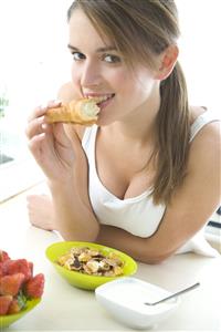 Mujer comiendo cereales, fresones y yogur.