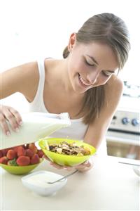 Mujer comiendo cereales con leche y fresones.