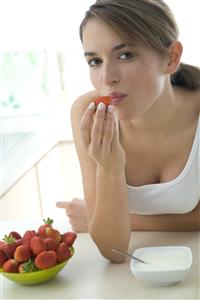 Mujer comiendo fresones y yogur. 