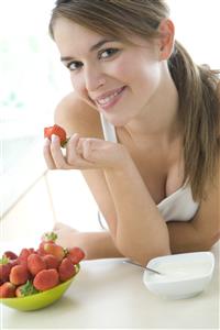 Mujer comiendo fresones y yogur. Primer plano.