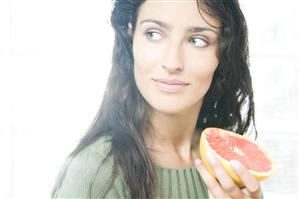 Mujer con medio pomelo en la mano. Primer plano.