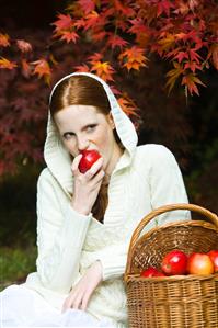 Young woman eating apple in park