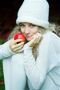 Young woman eating apple in park