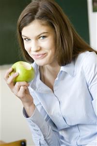 Chica adolescente comiendo una manzana en clase.