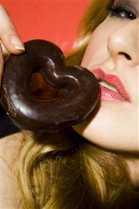 Young woman eating heart shaped cookie