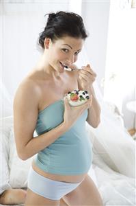 pregnant woman eating joghurt with fruits