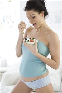 pregnant woman eating joghurt with fruits