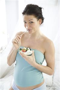 pregnant woman eating joghurt with fruits