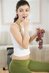 young woman eating grapes