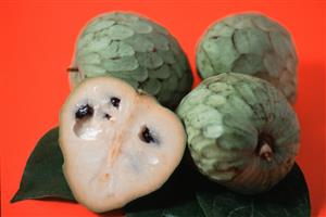 Varias chirimoyas, una abierta por la mitad. 