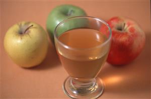 Vaso con sidra y tres manzanas.