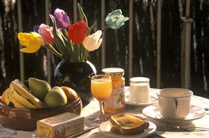 Desayuno preparado en una mesa y jarron con flores.