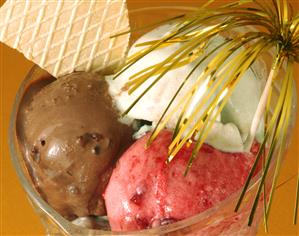 Tres bolas de helado de chocolate, fresa y nata.                               