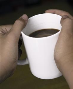 Manos de adolescente con un tazon de chocolate a la taza.                                