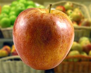 Manzana con cestas de manzanas desenfocadas detras.                           