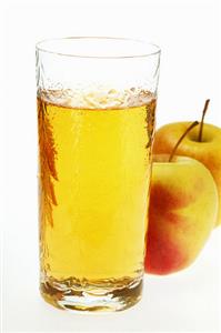 Glass of apple juice beside two fresh apples