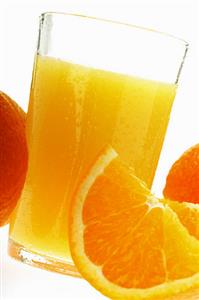 Orange juice in glass among oranges