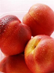 Nectarines with drops of water in plastic container