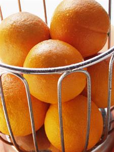 Oranges with drops of water in wire basket