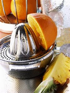 Orange on lemon squeezer, pineapple and ice cubes