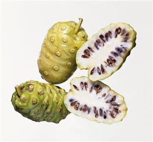 Two whole and one halved noni fruits