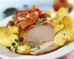 Roast loin of pork with apple wedges and bacon