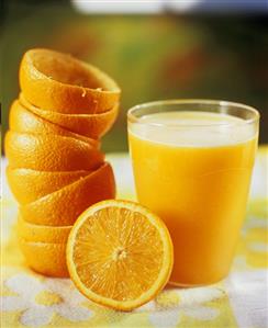 A glass of orange juice with squeezed oranges