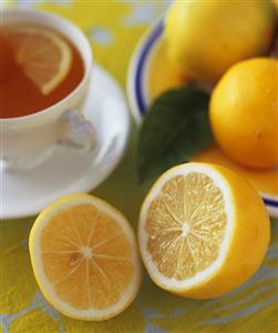 Cup of tea with whole and halved lemons