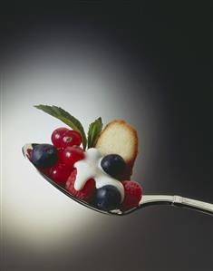 Fresh berries with cream and biscuit on spoon