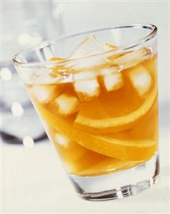 A glass of orange juice with ice cubes and orange slices