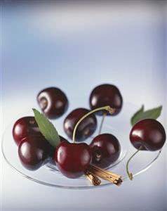 Cherries and cinnamon sticks on glass plate