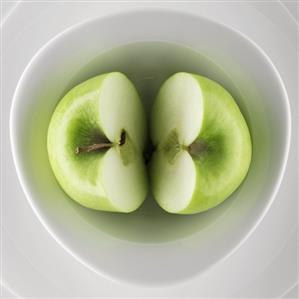 Halved green apple in a bowl