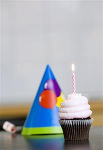 Chocolate cupcake with cream icing and one candle