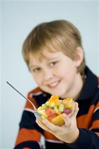 Boy holding a small bowl of fruit salad