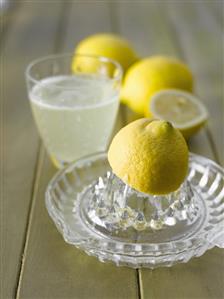 Lemon squeezer, lemons and a glass of hot lemon