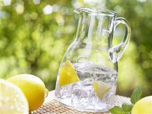 Glass jug of mineral water with lemon wedges and ice cubes