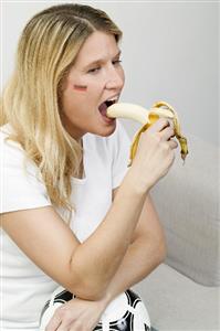 Young woman with football eating a banana