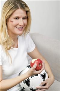 Young women with football eating an apple