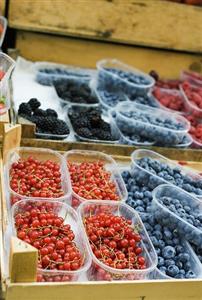 Various types of berries in plastic punnets at a market