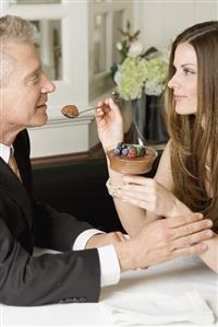 Woman offering man spoonful of chocolate cream in restaurant