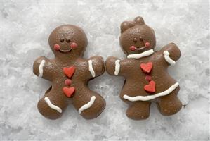 Two Christmassy chocolate-coated gingerbread people in snow