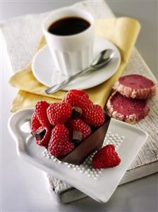 Small chocolate cake with raspberries and cup of coffee