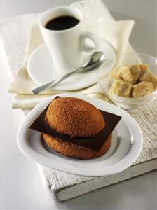 Small chocolate cake, cup of coffee and sugar cubes