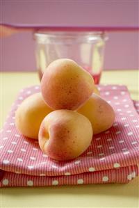 Apricots on tea towel, jam jar and cooking spoon