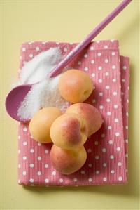 Apricots on tea towel, cooking spoon and sugar