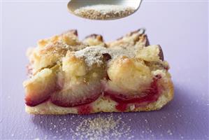 Sprinkling piece of plum cake with sugar