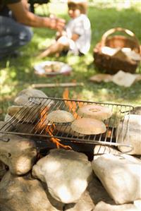 Melon on grill rack over camp-fire, child in background